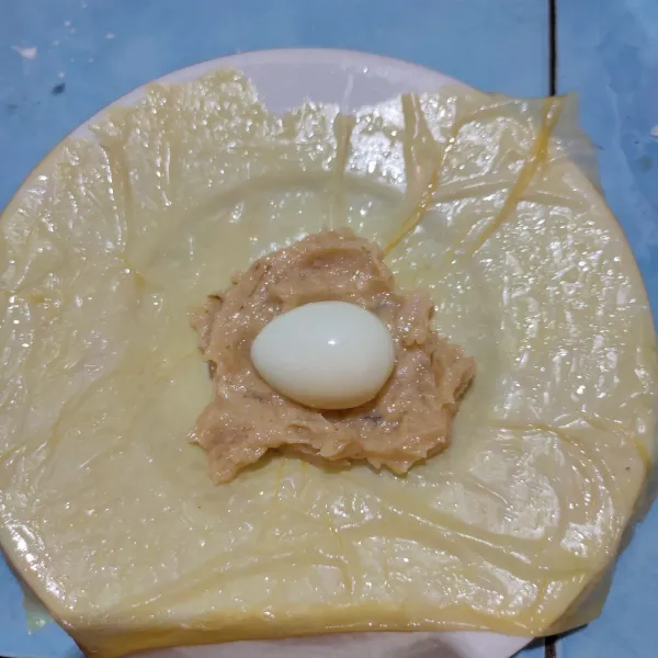 Ambil 1 lembar kulit tahu, rendam dalam air sebentar agar mudah dibentuk, beri isian lalu letakkan telur puyuh.