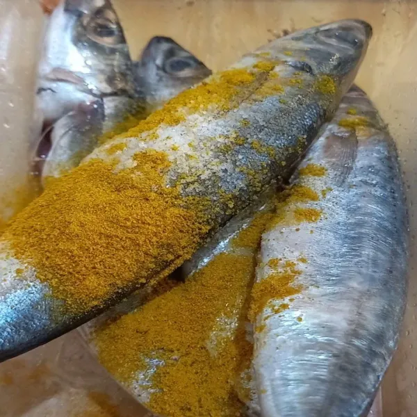 Bumbui ikan dengan kunyit bubuk dan garam.