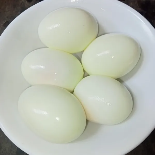 Rebus telur hingga matang, lalu kupas kulitnya.