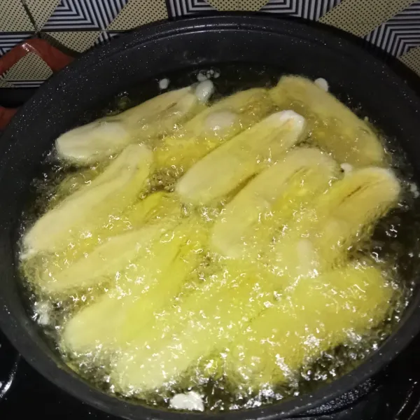 Goreng pisang dengan api sedang hingga matang dan keemasan, lalu angkat dan sajikan pisang dengan saus gula merah.