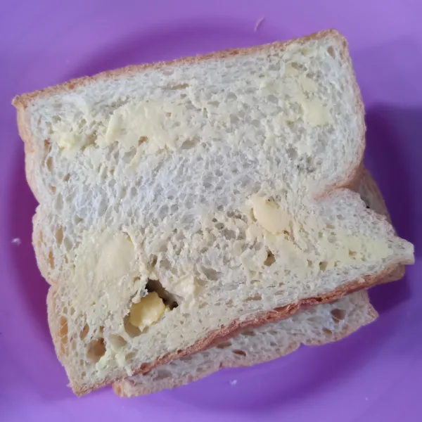 Tangkupkan dengan selembar roti tawar lainnya. Oles margarin di bagian atas.