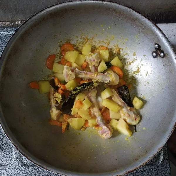 Masukkan wortel, kentang dan tulang ayam, aduk hingga bumbu rata.
