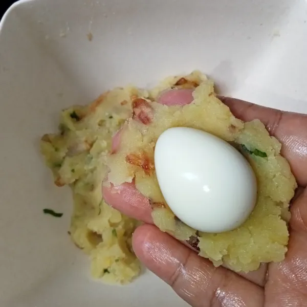Ambil campuran kentang secukupnya dan pipihkan, letakkan telur puyuh di atasnya.