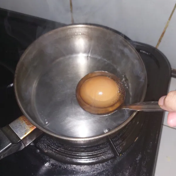 Masukkan telur dengan sendok sayur agar tangan aman dari air panas.
