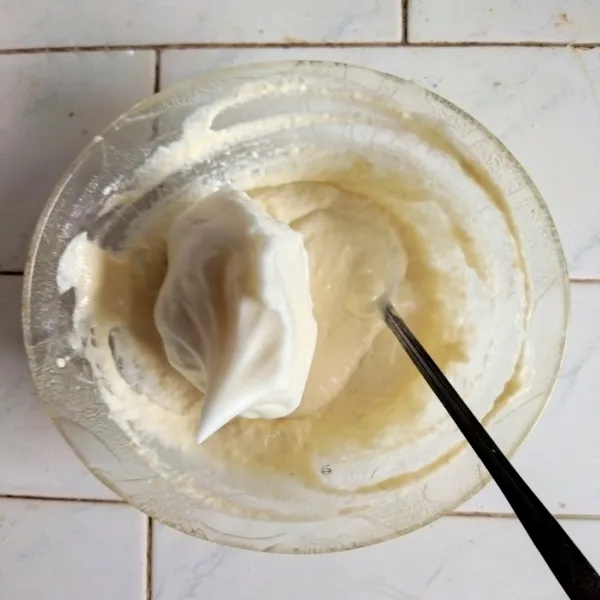 Masukkan meringue ke dalam adonan tepung secara berkala, aduk perlahan menggunakan sendok hingga tercampur rata.