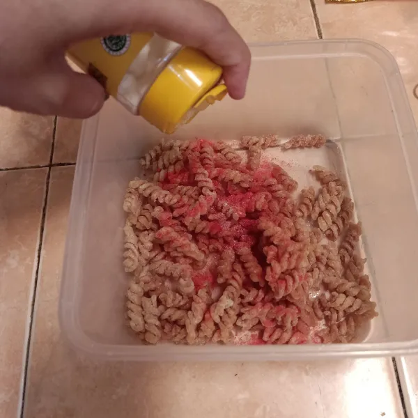 Taruh makaroni dalam wadah, beri bubuk bawang putih dan bumbu balado, aduk rata, sajikan.