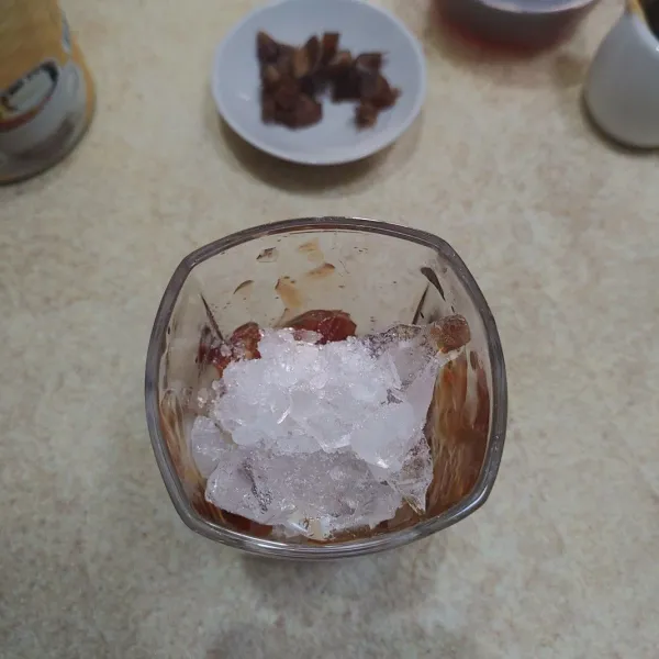 Tuang saus gula kurma ke dalam gelas, tambahkan es batu dan potongan kurma.