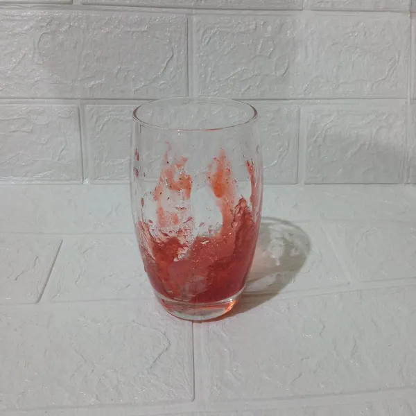 Tempelkan selai strawberry ke dalam sisi bagian dalam gelas dengan menggunakan sendok.