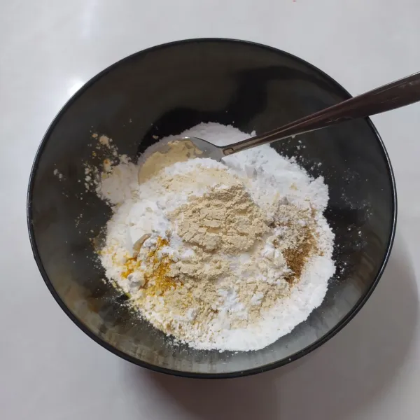 Dalam wadah campur jadi satu tepung beras, tepung tapioka, ketumbar bubuk, kunyit bubuk, bawang putih bubuk, garam dan kaldu jamur lalu aduk rata.