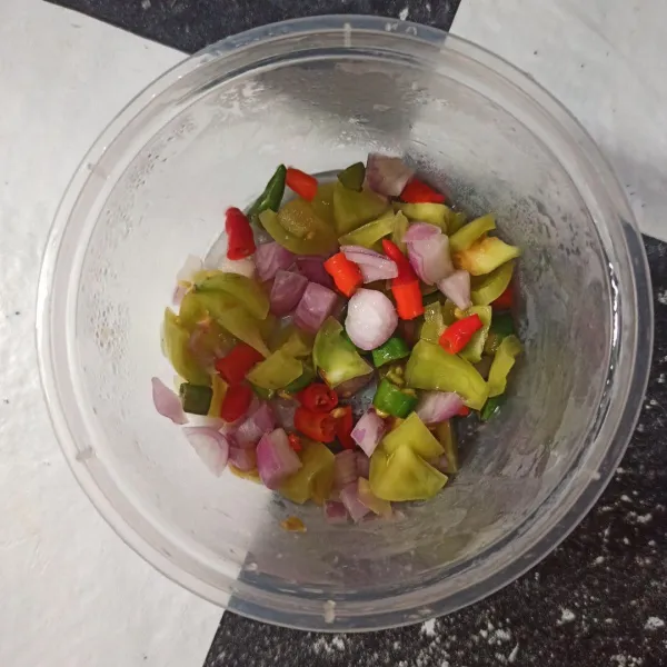 Potong tomat, cabai rawit hijau, cabai rawit merah, dan bawang merah, kemudian letakkan di satu wadah.