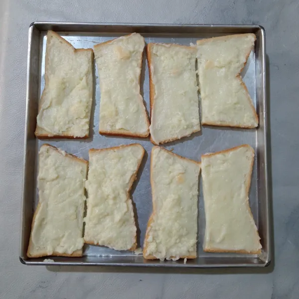 Kemudian oleskan milky cheese di atas roti secara merata, lalu taburkan dengan gula pasir.