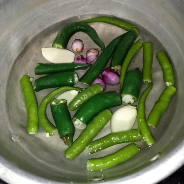 Rebus cabai hijau keriting, cabai hijau besar, bawang merah dan bawang putih hingga layu.