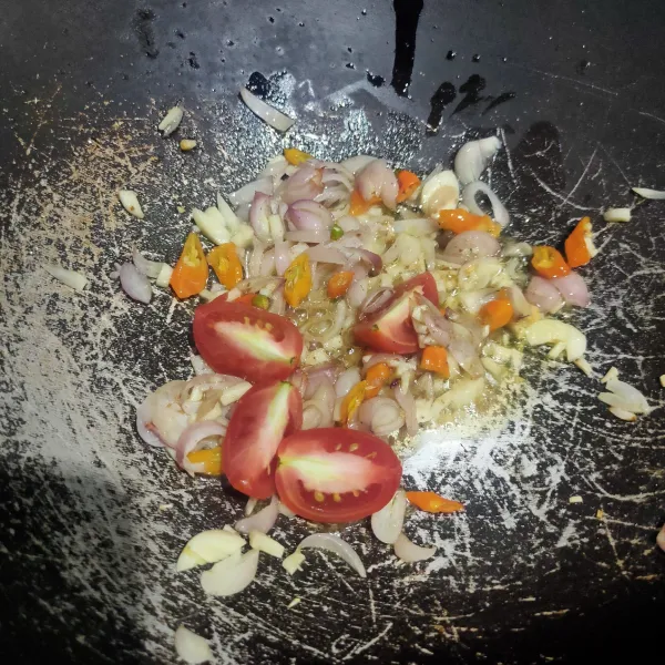 Tumis bumbu yang sudah dicincang dan terasi dengan sedikit minyak hingga harum lalu masukkan irisan tomat, aduk rata.