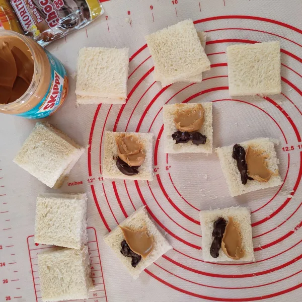 Beri selai coklat dan kacang di salah satu sisi roti tawar, lalu tutup.