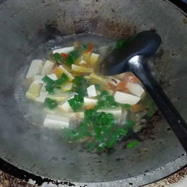 Setelah mendidih masukkan daun bawang, biarkan air agak menyusut.