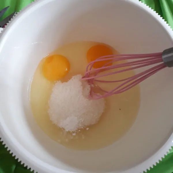 Siapkan wadah, masukkan telur, gula pasir, dan vanili bubuk. Kocok pakai whisk hingga rata.