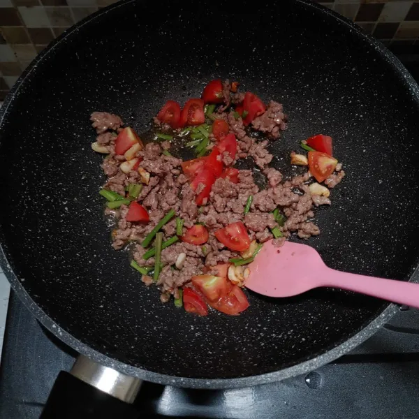 Tumis bawang putih hingga harum, masukkan daging sapi masak hingga daging berubah warna. Lalu masukkan irisan tomat dan ketumbar. Aduk.