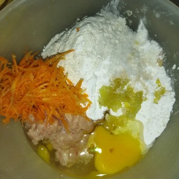 Siapkan wadah, masukkan daging ayam yang sudah dicincang halus, wortel yang sudah diserut, tepung terigu, tepung sagu, telur, garam, dan kaldu jamur.