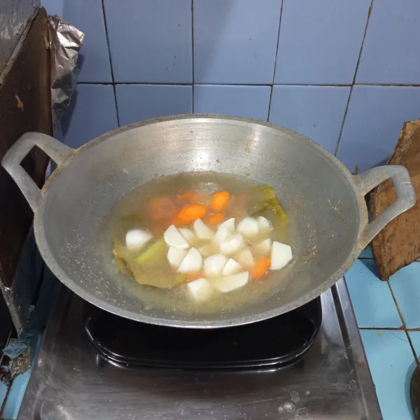 Lalu tuang air, masukkan wortel dan bakso ikan, masak hingga mendidih dan wortel setengah matang.