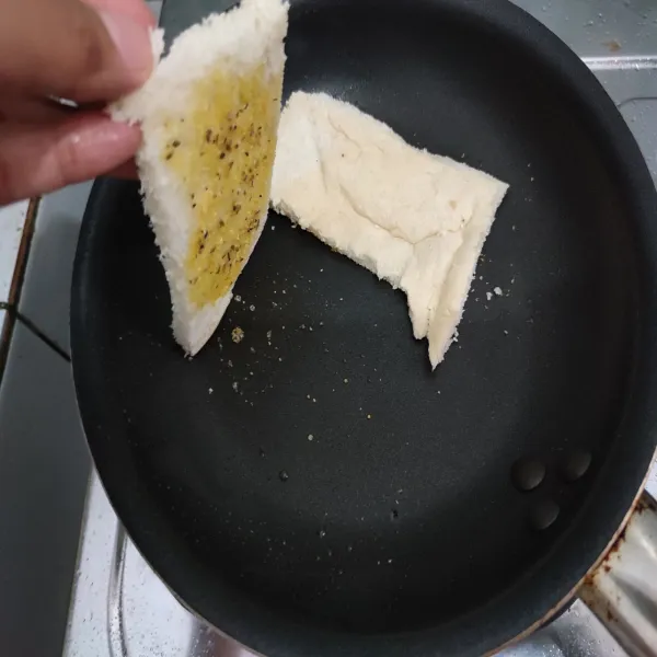 Panggang roti diatas teflon dengan api kecil dengan bagian yang dioles ada di bagian bawah.