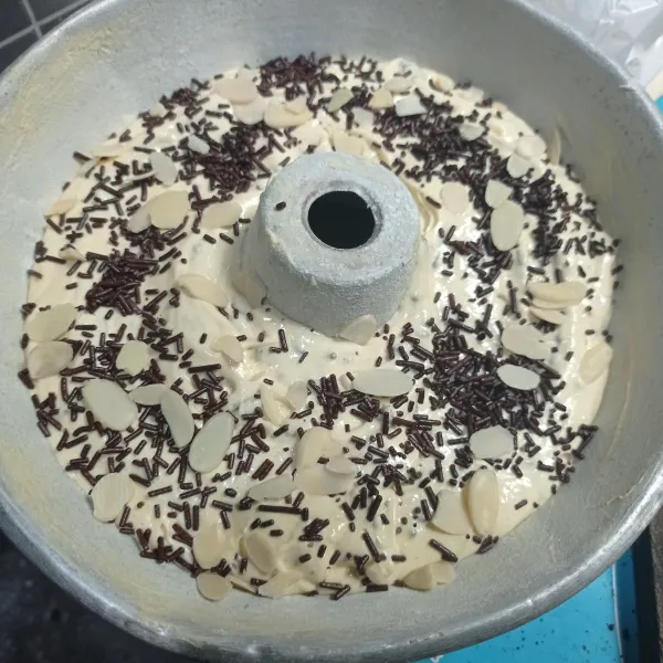 Tuang pada loyang yang sudah dioles margarin dan ditabur tepung, hentakan dan beri toping meses coklat dan almond slice.