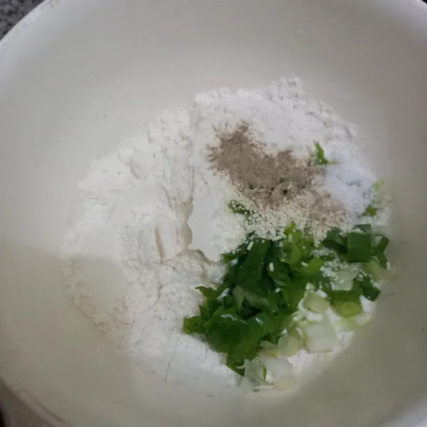 Dalam wadah campur tepung terigu, garam, kaldu jamur, merica bubuk, dan bawang daun, lalu aduk rata.