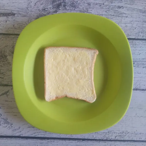 Olesi permukaan roti tawar dengan margarin.