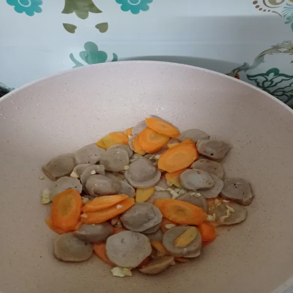 Masukkan bakso dan wortel, tumis hingga wortel agak layu. Kemudian tuang air.