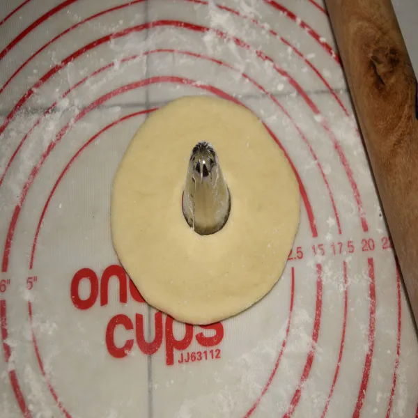 Pipihkan adonan dengan rolling pin dan bentuk bulat lalu lubangi tengahnya.