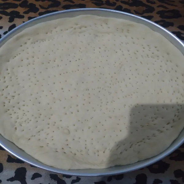 Siapkan loyang bulat tipis dengan diameter 25 cm.
Olesi dengan margarin tipis-tipis.
Kempiskan adonan dan gilas tipis, ratakan ke atas loyang.
Tusuk-tusuk adonan dengan garpu, taburi dengan aneka topping.