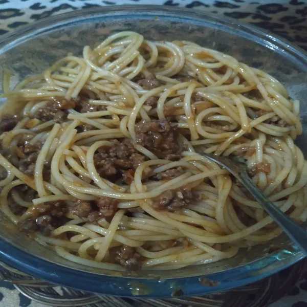 Masukkan saus beef bolognese ke dalam mangkuk yang berisi spaghetti. Aduk rata.