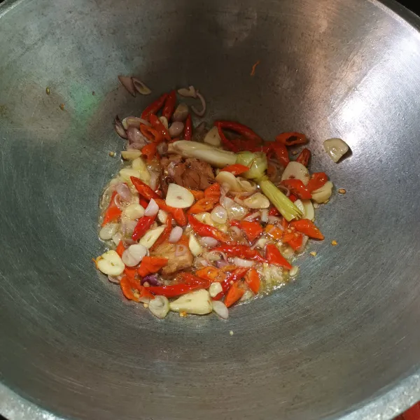 Panaskan minyak goreng, tumis bawang merah dan bawang putih sampai harum, lalu masukkan cabai, lengkuas dan serai.
Aduk sampai cabai layu.