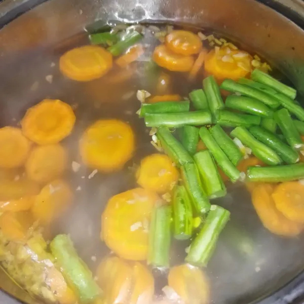 Lalu masak air secukupnya, jika sudah mendidih masukkan wortel dan buncis, lalu beri bawang putih cincang yang sudah di goreng. Masak hingga wortel setengah matang.