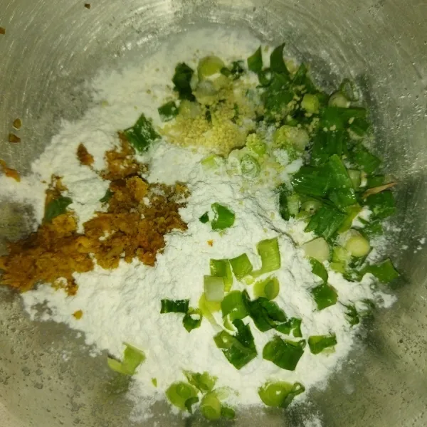Siapkan wadah, masukkan tepung terigu, bumbu yang sudah dihaluskan, garam, kaldu bubuk dan daun bawang.