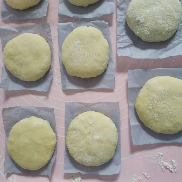 Gulingkan adonan ke dalam tepung, kemudian pipihkan menggunakan telapak tangan lalu letakkan adonan diatas kertas kue dan istirahatkan kembali selama 45 menit.