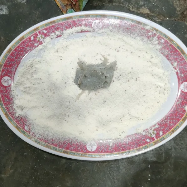 Tuang tepung bumbu dalam piring, masukkan sedikit teri basah ke dalam tepung bumbu.