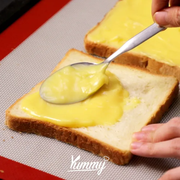 Tambahkan adonan keju ke atas roti tawar, lalu ratakan dengan bantuan spatula atau pisau.