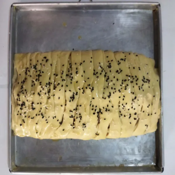 Letakan pada loyang, olesi permukaannya dengan kocokan telur, dan tabur biji wijen.