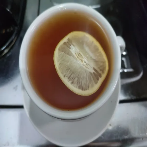 Masukkan potongan lemon ke dalam gelas, sajikan hangat.