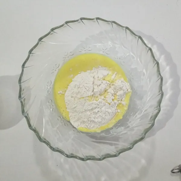 Masukkan tepung terigu ke dalam mangkuk, lalu tuang santan sedikit demi sedikit sambil terus di aduk agar tidak ada yang bergerindil dan adonan menjadi licin.