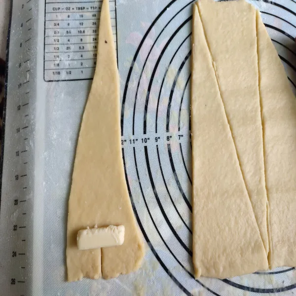Ambil satu bagian kulit pastry, potong sedikit di bagian ujung segitiganya.
Letakkan keju di atasnya.