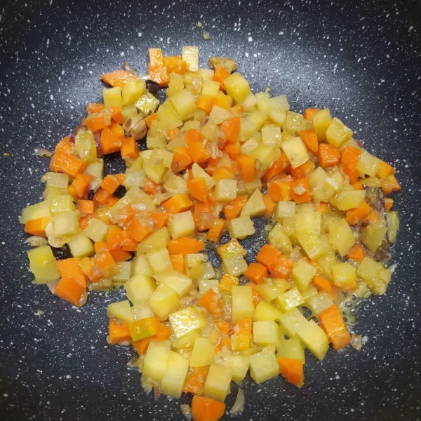 Masukkan irisan wortel dan kentang, tumis sampai ½ matang. (Tambahkan sedikit air kaldu jika takut gosong)