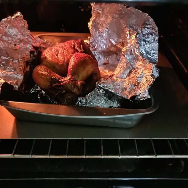 Panaskan oven 15 menit sebelumnya. Oven ayam dengan suhu 150°C dengan menutup seluruh tubuh ayam dengan aluminium foil selama 45 menit. Lalu buka penutup aluminium foil atas dan panggang lagi selama 15 menit.