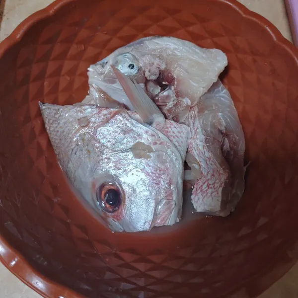 Belah menjadi 2 bagian kepala ikan, cuci bersih dan lumuri dengan perasan jeruk lemon. 
Diamkan sebentar.