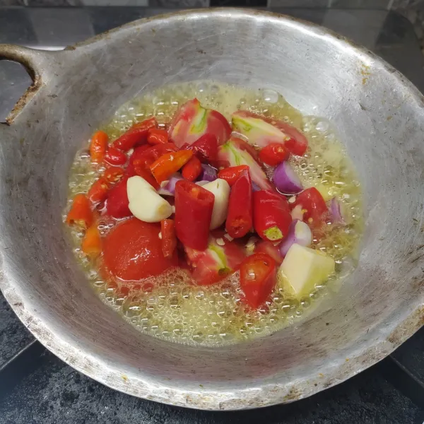 Untuk membuat sambal, goreng cabai merah, cabai rawit, tomat, bawang merah dan bawang putih sampai matang.