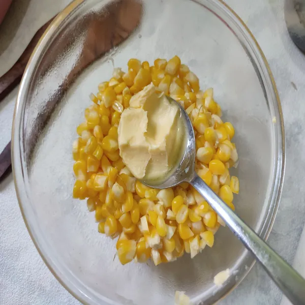 Pindahkan jagung yang sudah dikukus ke dalam wadah, kemudian campurkan dengan butter, aduk rata.