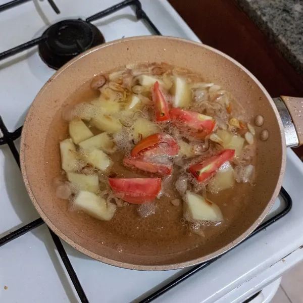 Tambahkan air biarkan mendidih, masukkan kentang dan tomat, masak hingga kentang setengah matang.