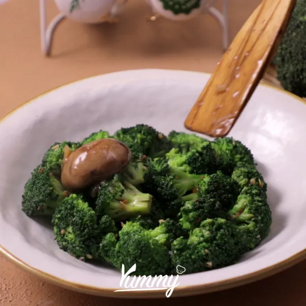 Tata brokoli di atas piring saji, lalu tuangkan tumisan jamur di atasnya.