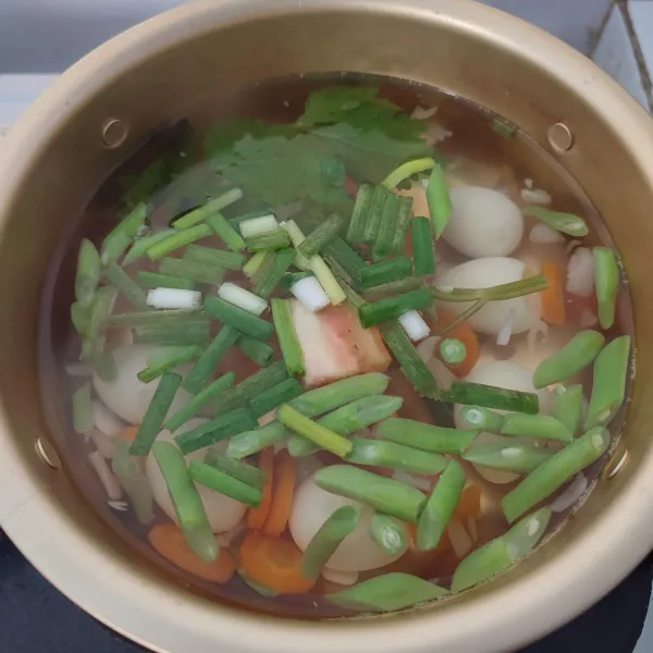 Setelah buncis empuk, masukkan telur puyuh, daun bawang serta tambahkan air sampai ¾ bagian panci.