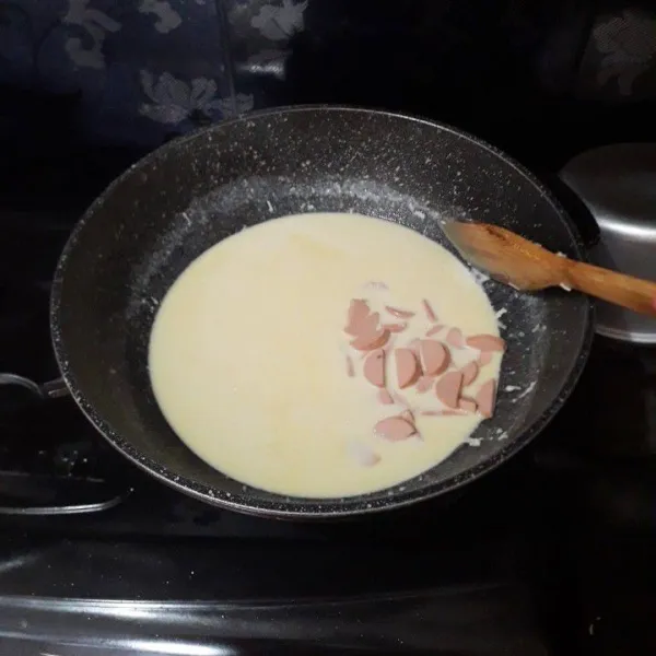 Masukkan susu, aduk lagi hingga tidak ada yang bergerindil, lalu masukkan sosis.